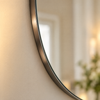 Close-up of the oval mirror's slim metal frame edge