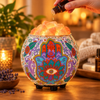 Close-up of a hand adding a few drops of essential oil onto the glowing pink salt crystals in the carved bowl