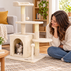 A kitten peeking out of the cozy condo of the compact cat tree while its owner sits nearby on the floor smiling